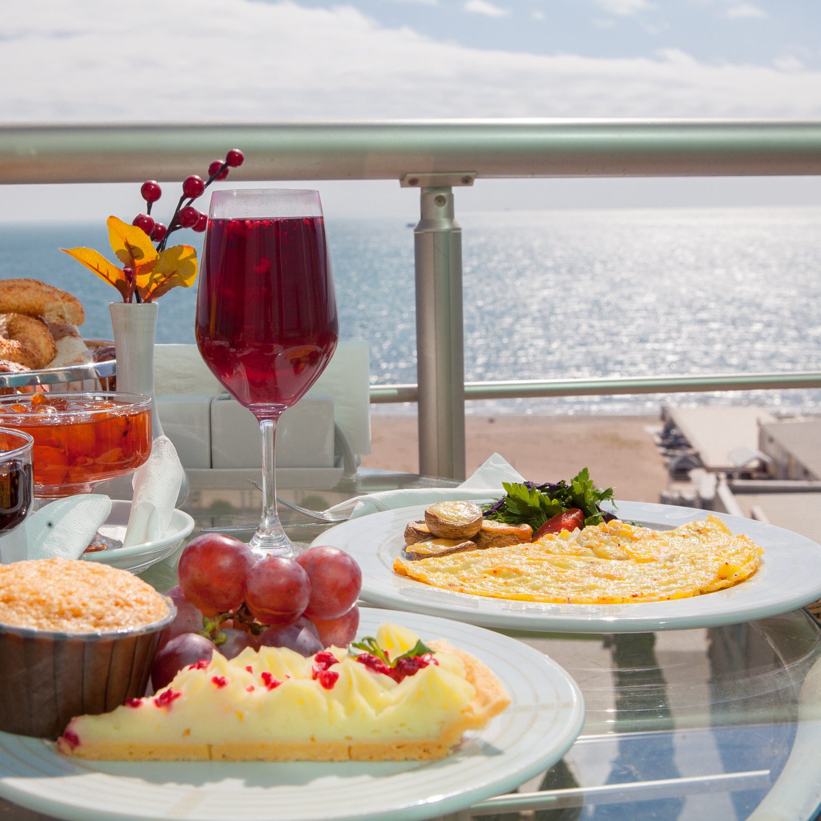 Side view breakfast with baked and grape and omelette in white plate on the balc ony by the sea