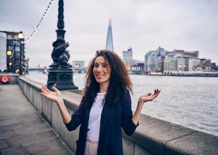 portrait-woman-gesturing-while-standing-against-thames-river-city_1048944-15157567